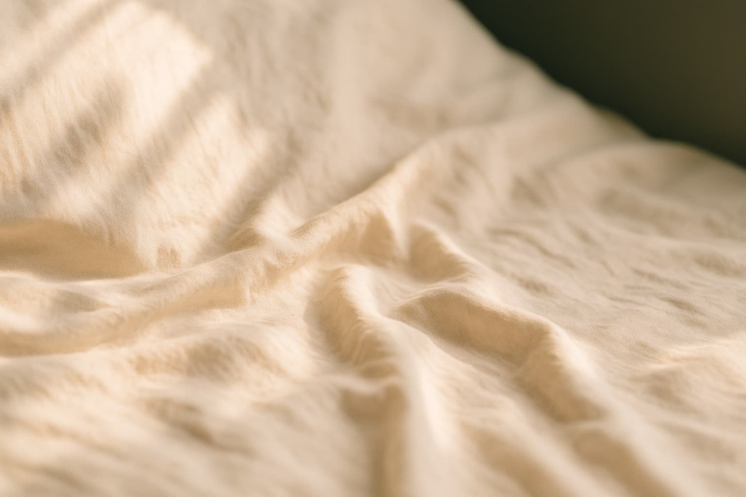 Folded linen on a treatment couch, lit by late-afternoon window light